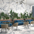 Modern interior with blue sofas, beige chairs, and decorative plants against a marble wall.