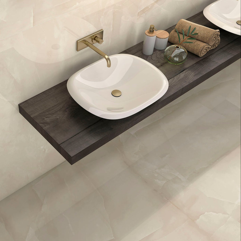 Bathroom sink with wooden shelf and decorative items on a tiled wall.